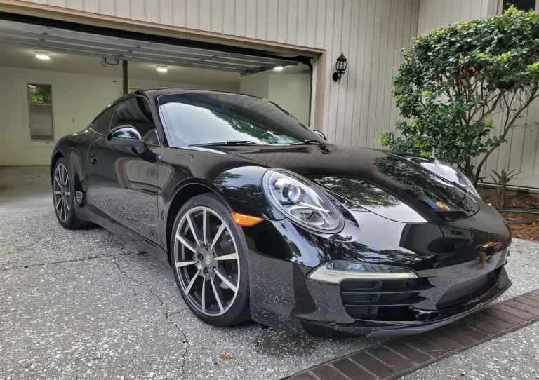 Black Porsche 911 Carrera in a driveway