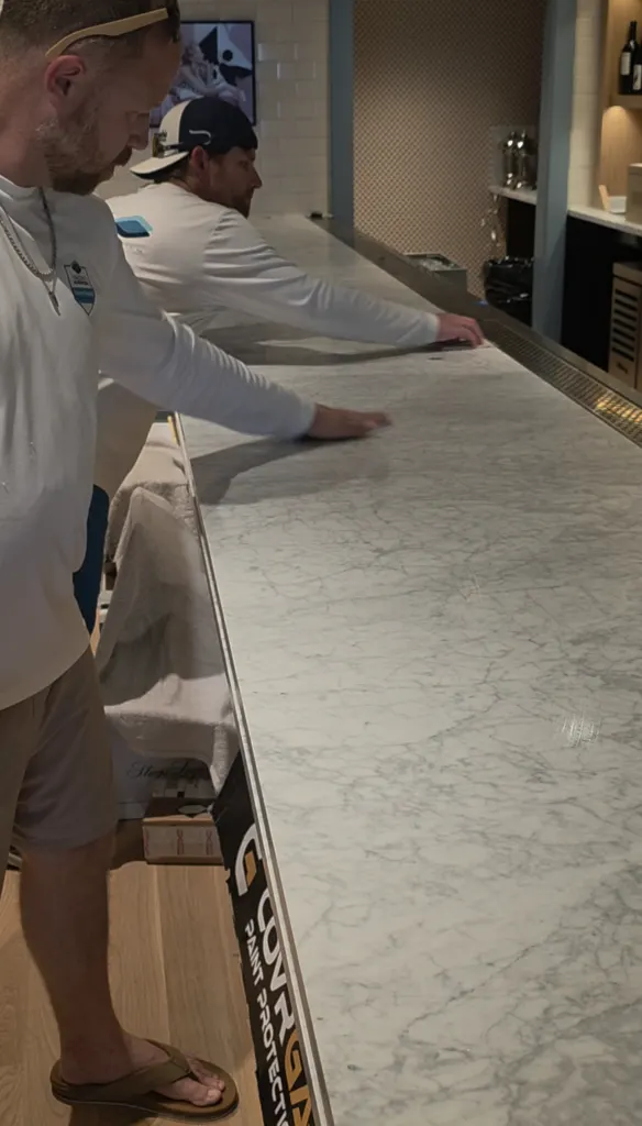 Laying clear protection film on a marble bar top at a Savannah bar